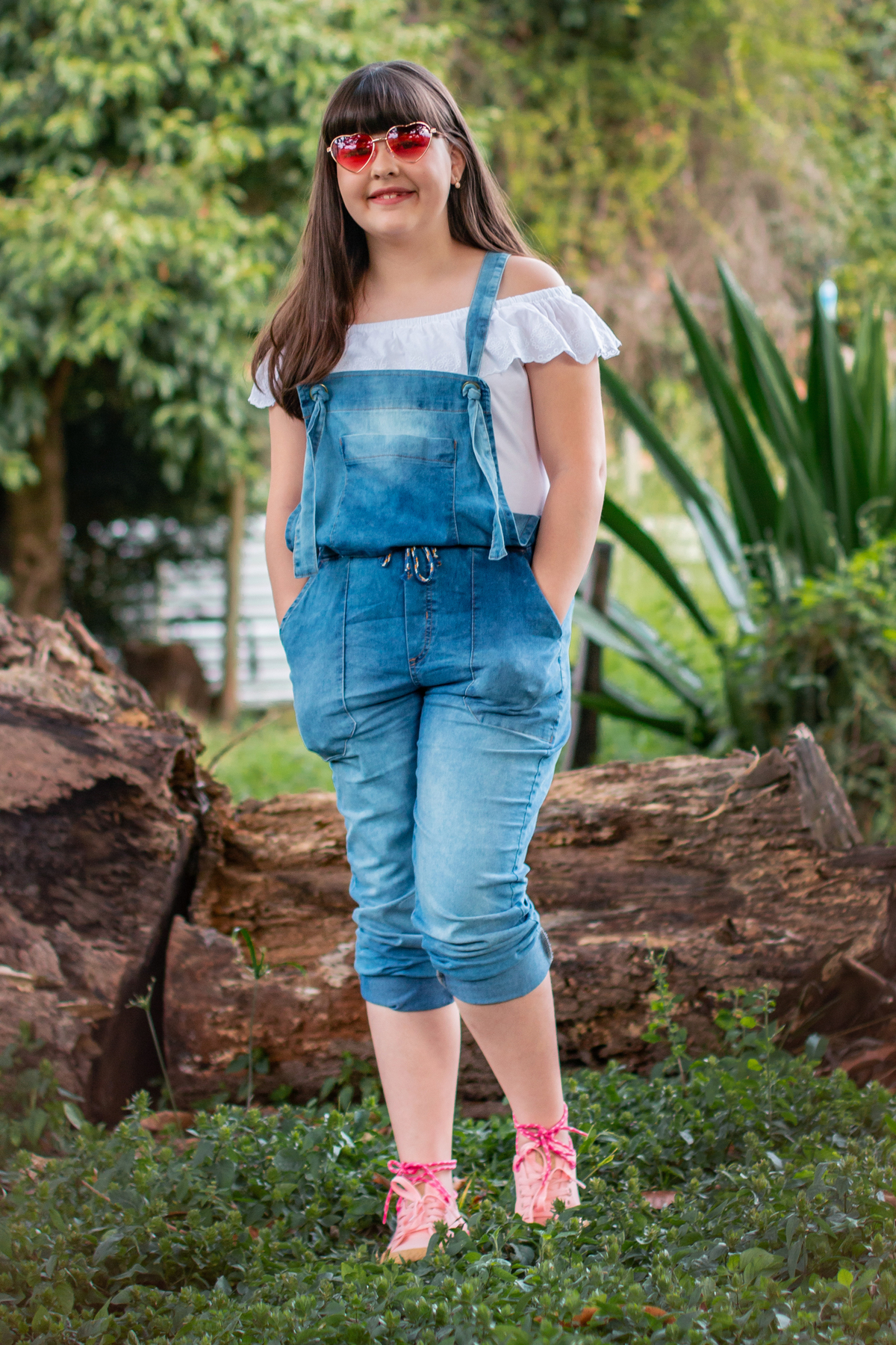 Ensaio de fotos ao ar livre com muito verde, menina com macacão jeans linda, toda feliz comemorando seu aniversário de 10 anos com óculos decoração estúdio em Santo Antônio de Pádua no Rio de Janeiro.