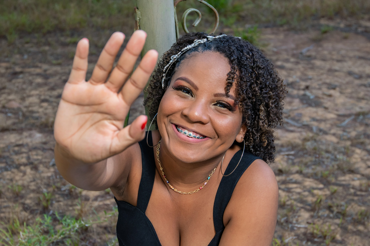Aniversariante linda de 15 anos, com cabelo cacheado em um dia lindo com muito verde ao por do sol parque municipal de Miracema em seu ensaio de 15 Anos. No interior do Rio de Janeiro.