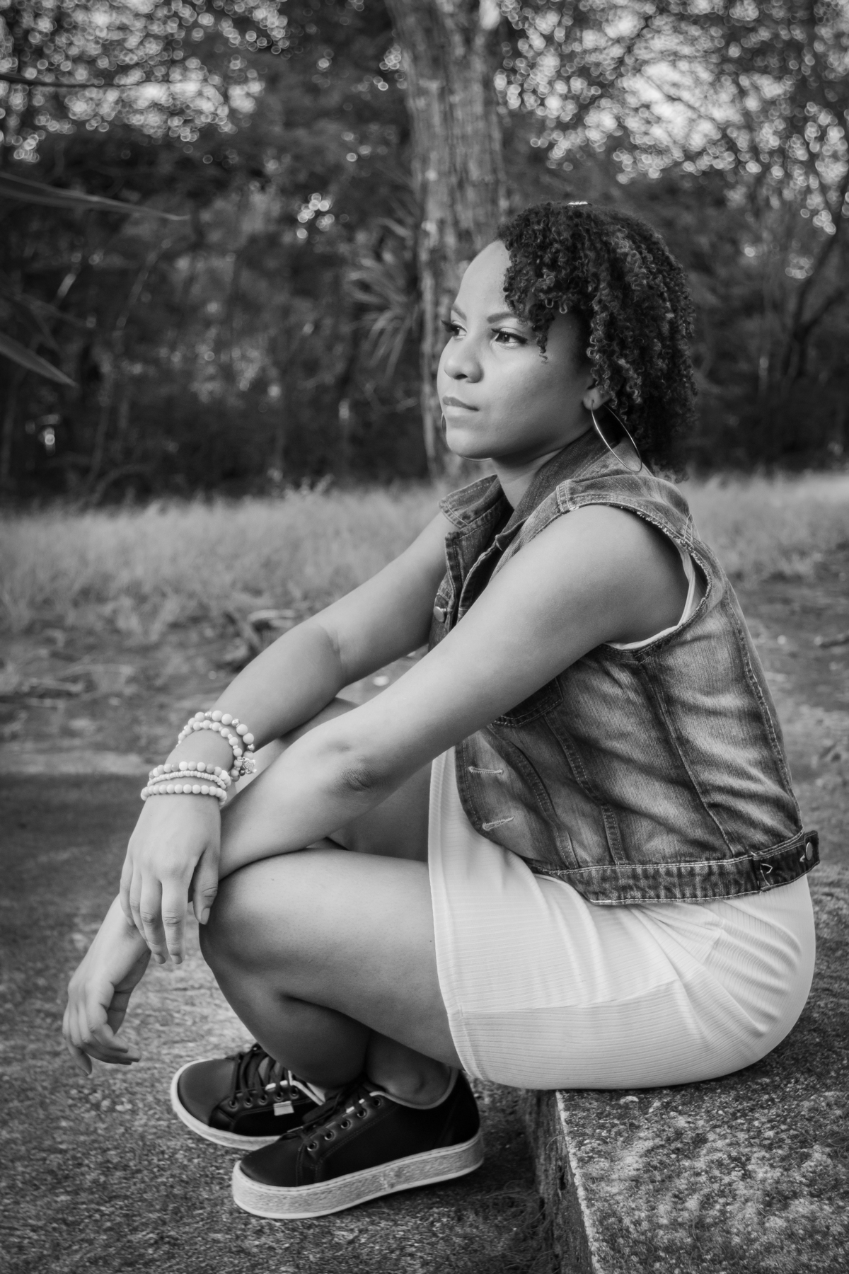 Aniversariante linda com jaqueta jeans em um campo florido com um céu azul perfeito no parque municipal de Miracema em seu ensaio de 15 Anos. No interior do Rio de Janeiro. Foto preta e branco