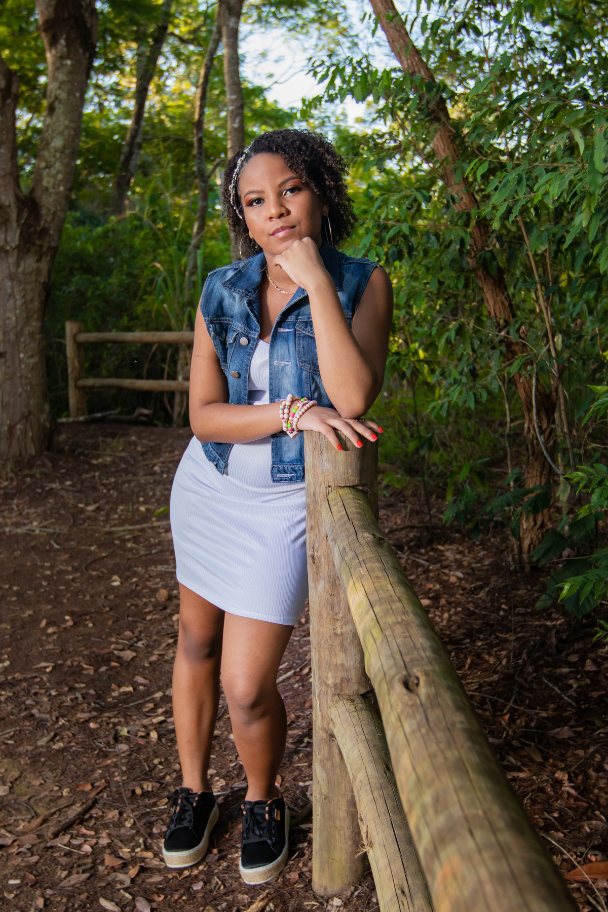 Aniversariante linda com jaqueta jeans em um campo florido com um céu azul perfeito no parque municipal de Miracema em seu ensaio de 15 Anos. No interior do Rio de Janeiro.