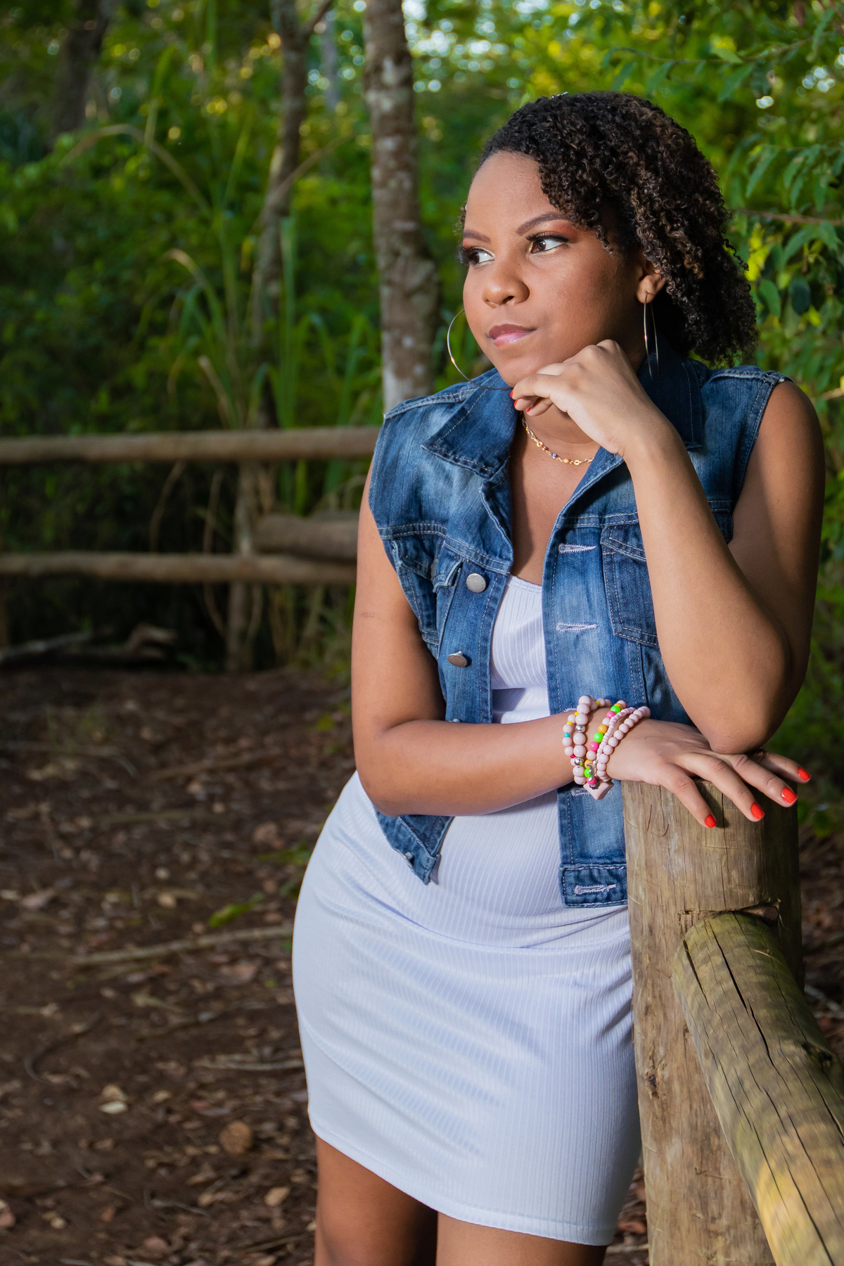 Aniversariante linda com jaqueta jeans em um campo florido com um céu azul perfeito no parque municipal de Miracema em seu ensaio de 15 Anos. No interior do Rio de Janeiro.