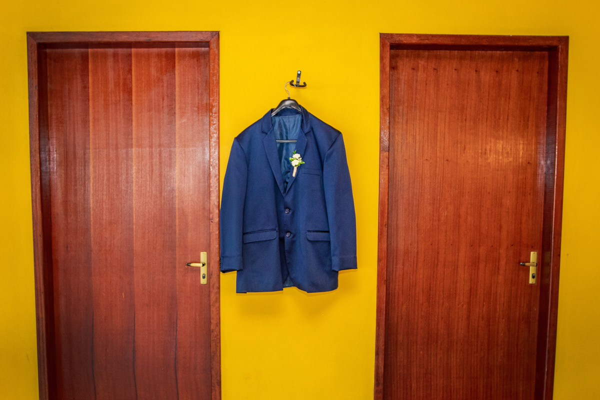 Terno do noivo azul escuro pendurando durante fotos do seu Making Of em casamento em Santo Antônio de Pádua interior do Rio de Janeiro.