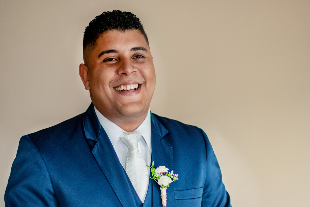 Noivo sorrindo com seu Terno noivo azul escuro durante fotos do seu Making Of em casamento em Santo Antônio de Pádua interior do Rio de Janeiro. Minutos antes da cerimônia de casamento.