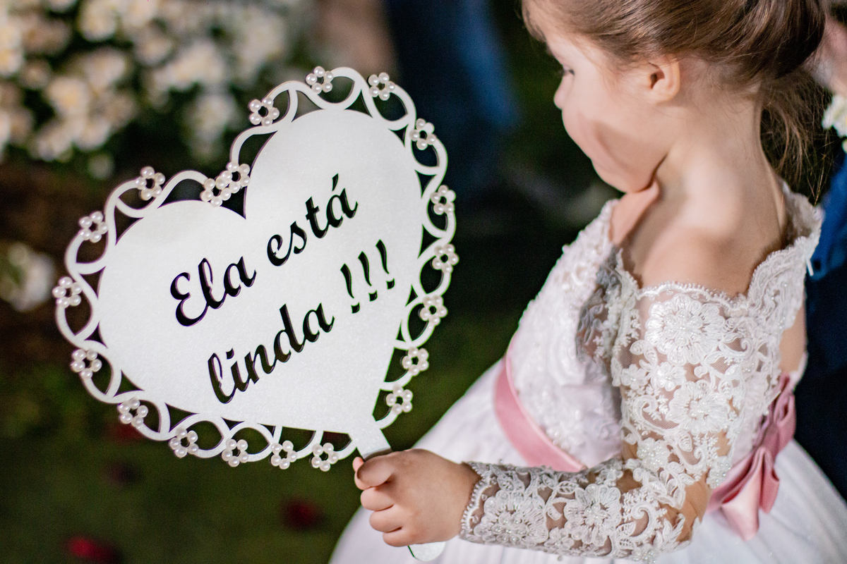 Dama de honra com plaquinha escrito: Ela está linda durante cerimônia de casamento ao ar livre em Santo Antônio de Pádua interior do Rio de Janeiro.