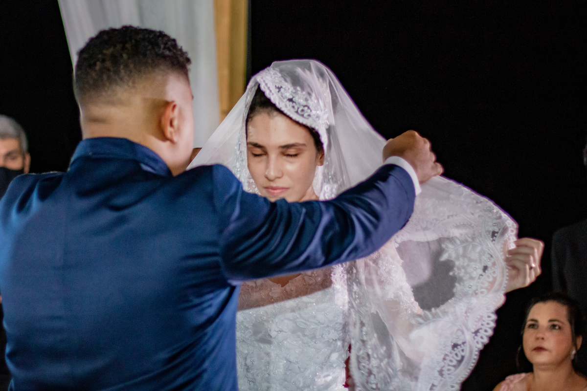 Noivos chorando durante oração no casamento casamento ao ar livre. Noivo com terno azul escuro e noiva com vestido com flores em 3D e véu na cabeça em Santo Antônio de Pádua interior do Rio de Janeiro.