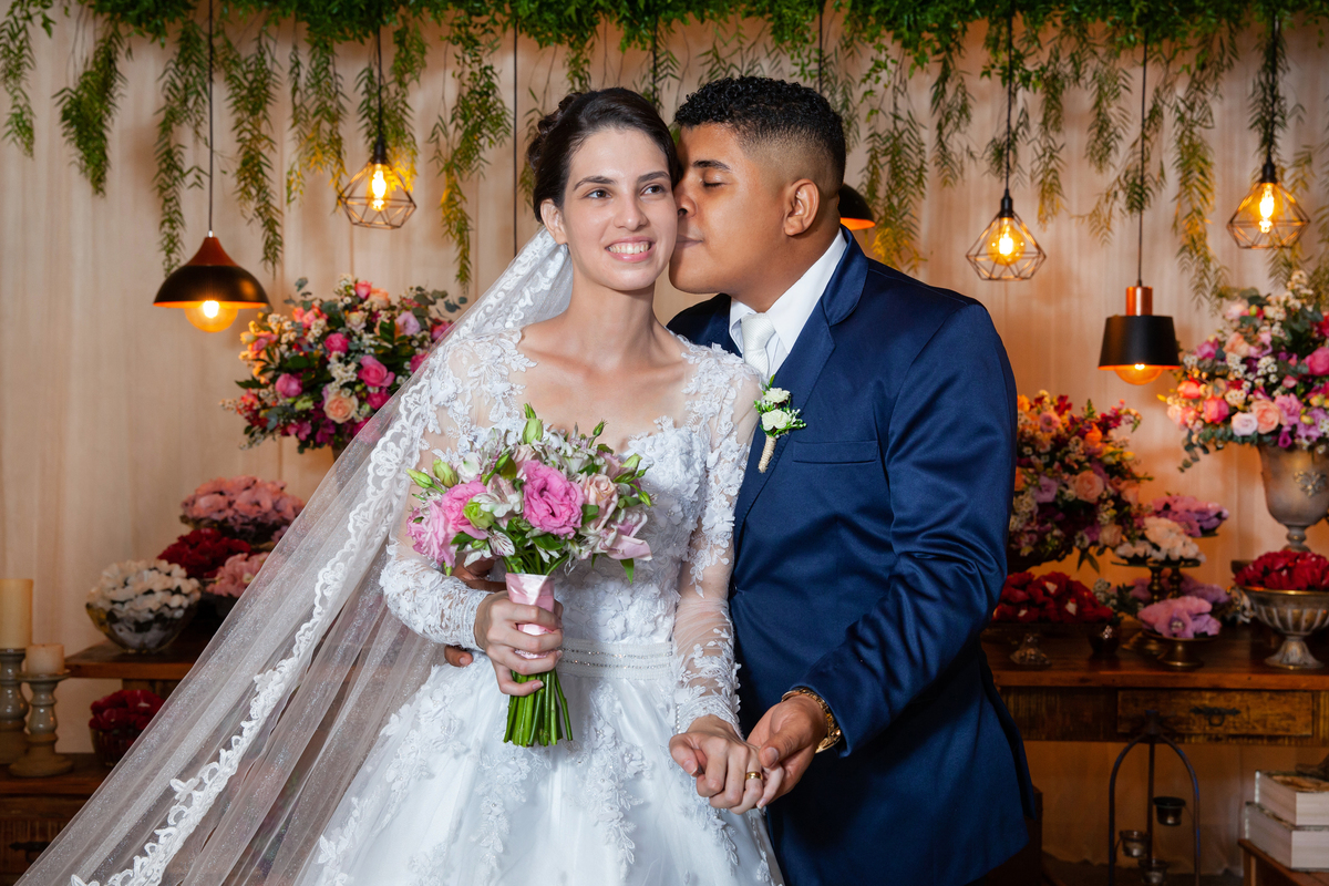 Noivos fazendo a sessão de fotos depois da cerimônia de casamento durante a festa em Santo Antônio de Pádua interior do Rio de Janeiro. Noiva com buquê em tons de rosa e noivo de terno azul escuro.