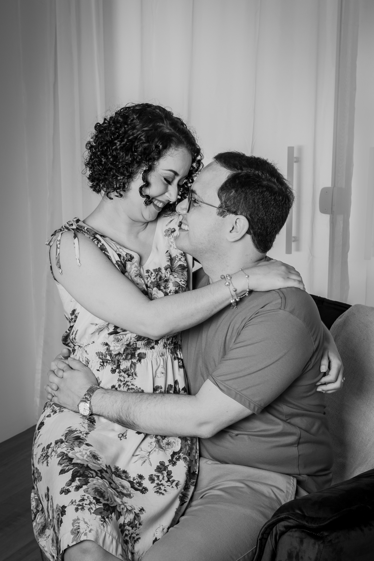 Ensaio casal em estúdio fotográfico para comemorar 10 anos de casados. Esposa sentada na perna do esposo. Em stúdio em Santo Antônio de Pádua no interior do Rio de Janeiro. Foto preta e branca.