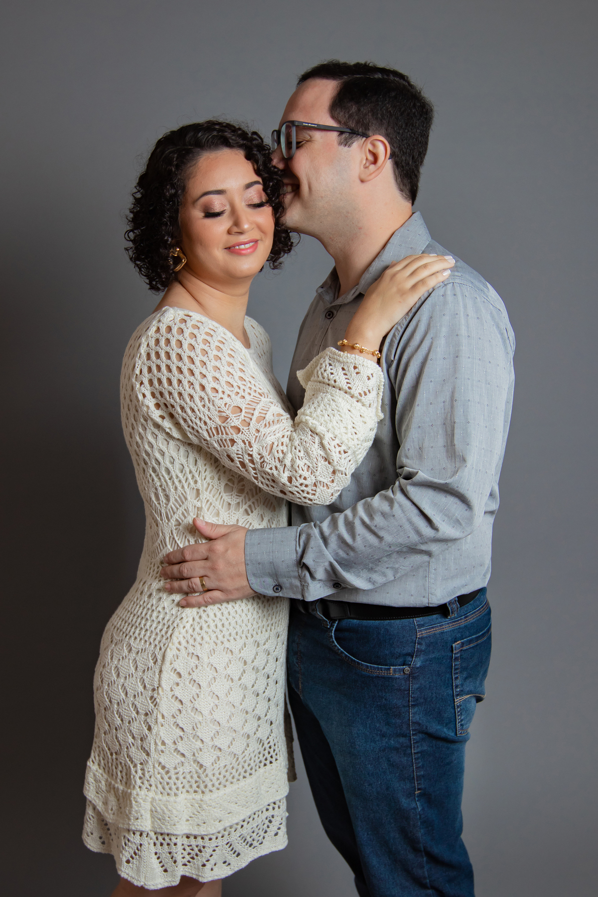 Ensaio casal em estúdio fotográfico para comemorar 10 anos de casados. Foto do casal de mãos dadas sorrindo um para o outro. Ela com vestido branco de linha e ele de camisa social em stúdio em Santo Antônio de Pádua no interior do Rio de Janeiro.