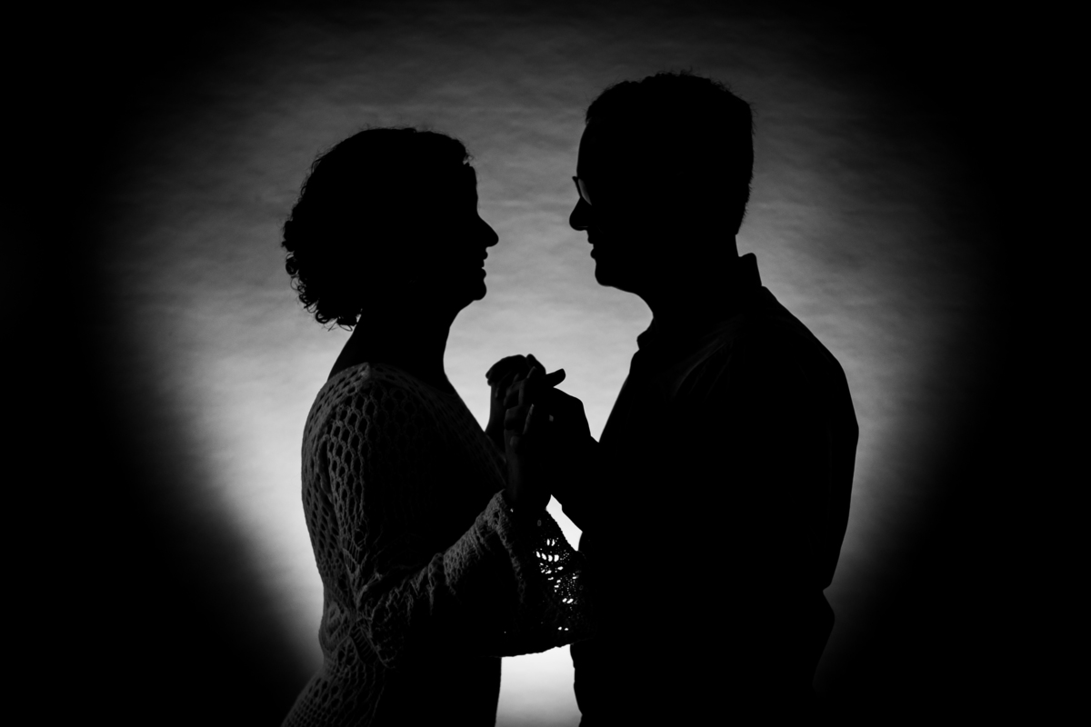 Ensaio casal em estúdio fotográfico para comemorar 10 anos de casados. Foto do casal de mãos dadas sorrindo um para o outro. Foto preto e branco em stúdio em Santo Antônio de Pádua no interior do Rio de Janeiro.