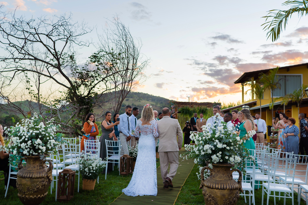 Noiva entrando com seu pai para seu casamento ao ar livre, durante o fim de 
 

tarde com um pôr do sol maravilhoso em Santo Antônio de Pádua no interior do Rio de Janeiro.