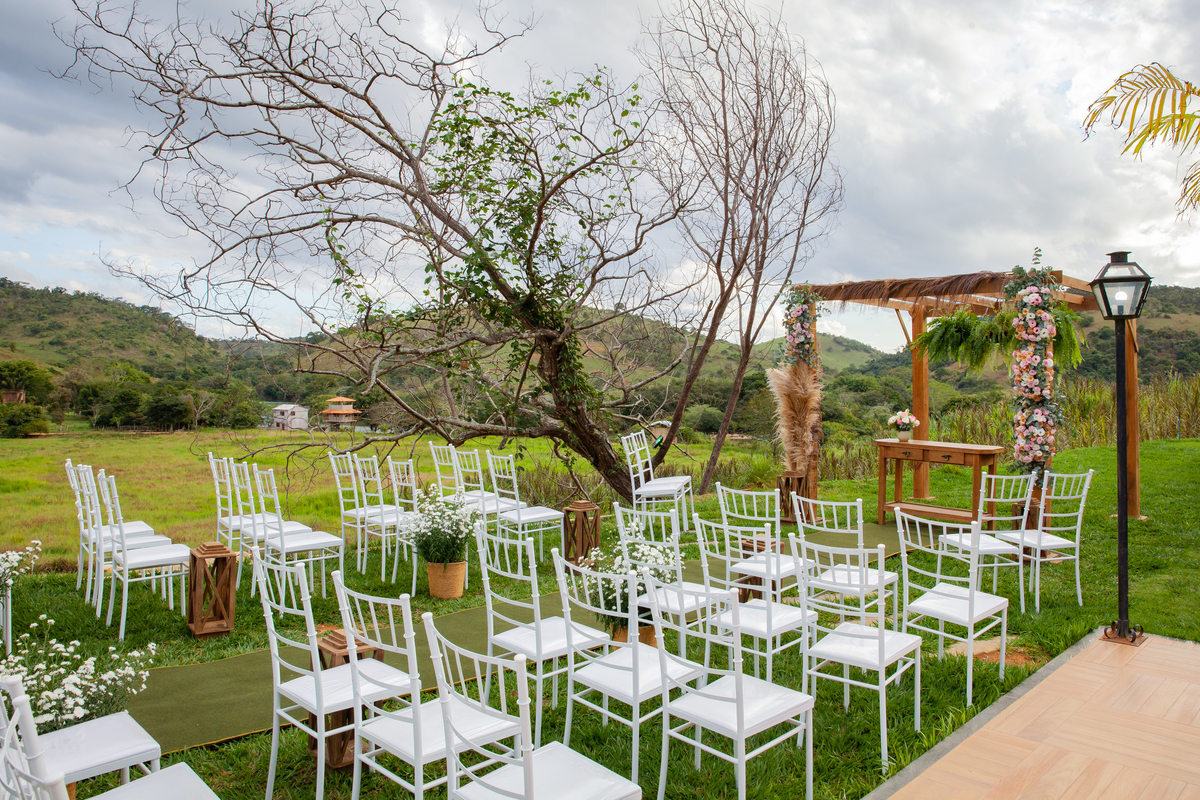 Casamento durante o dia ao ar livre, em um pôr do sol perfeito, com cadeiras de ferro lindas e brancas de debaixo de uma arvore seca em Santo Antônio de Pádua interior do Rio de Janeiro.