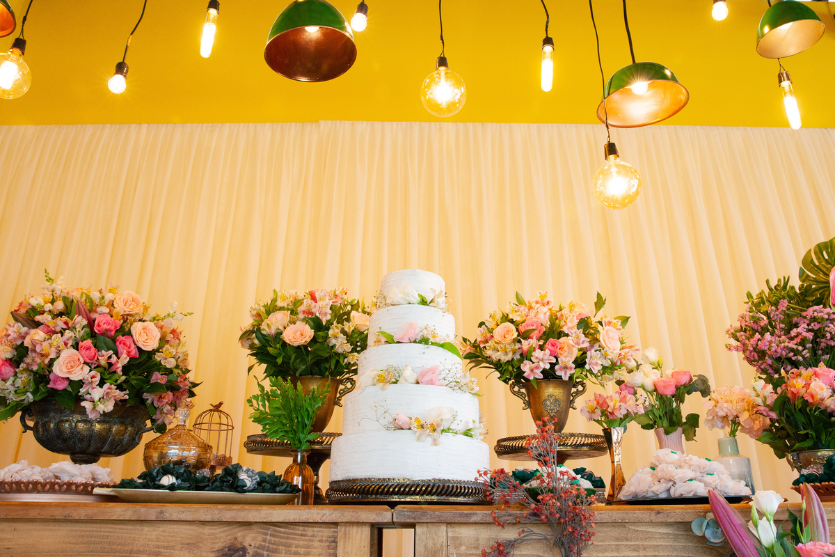 Decoração de casamento, com lâmpadas penduradas, moveis rústicos e flores coloridas. Casamento durante o dia ao ar livre  em Santo Antônio de Pádua no interior do Rio de Janeiro.