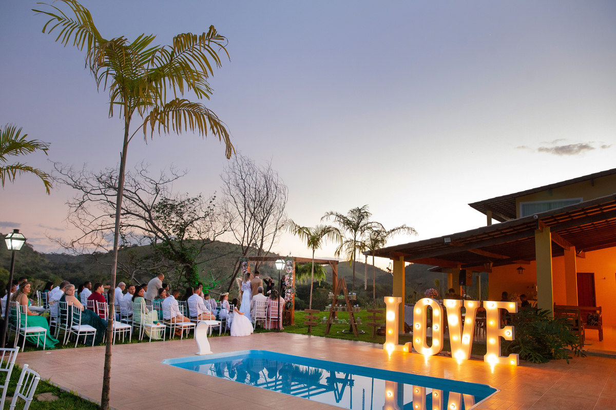 Noivos felizes durante cerimonia de casamento ao ar livre, noiva com vestido sereia e noivo com terno dourado e gravata borboleta. Casamento durante o dia com um pôr do sol maravilhoso em Santo Antônio de Pádua no interior do Rio de Janeiro.