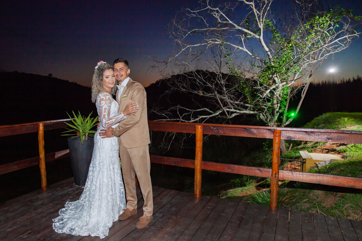 Noivo se abraçando  durante sessão de fotos ao pôr do sol maravilhoso em um píer em casamento durante o dia ao ar livre  em Santo Antônio de Pádua no interior do Rio de Janeiro. Noiva com vestido sereia e noivo com terno dourado e gravata borboleta.