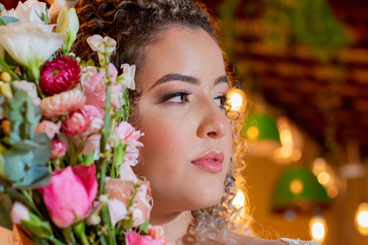 Noiva com vestido sereia, muito feliz  no meio da decoração de casamento, com lâmpadas penduradas, moveis rústicos e flores coloridas. Casamento durante o dia ao ar livre  em Santo Antônio de Pádua no interior do Rio de Janeiro.