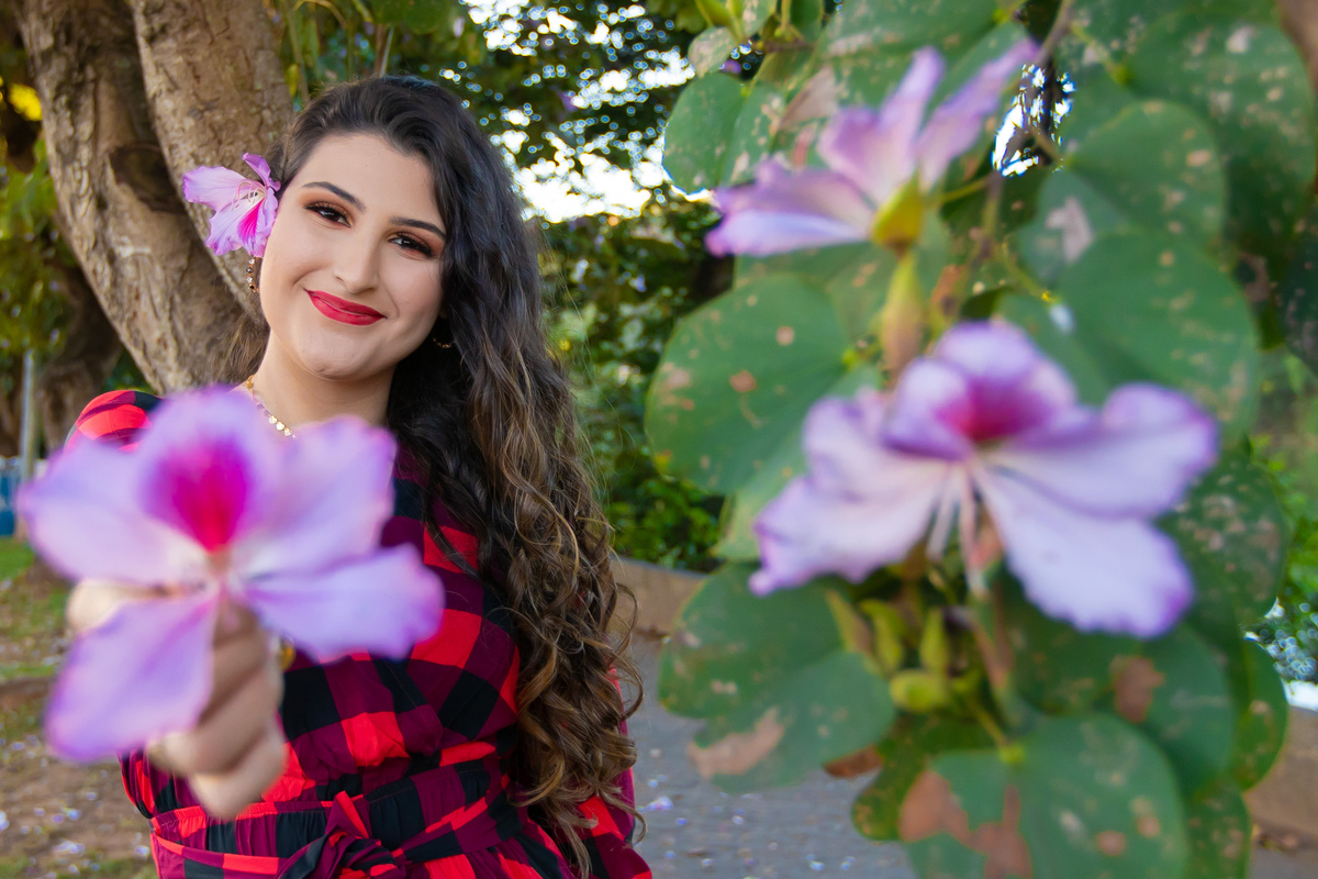 Ensaio de 15 , debutante sorrindo,  vestindo roupa xadrez em pôr do sol em um dia ensolarado em Santo Antônio de Pádua no interior do Rio de Janeiro.