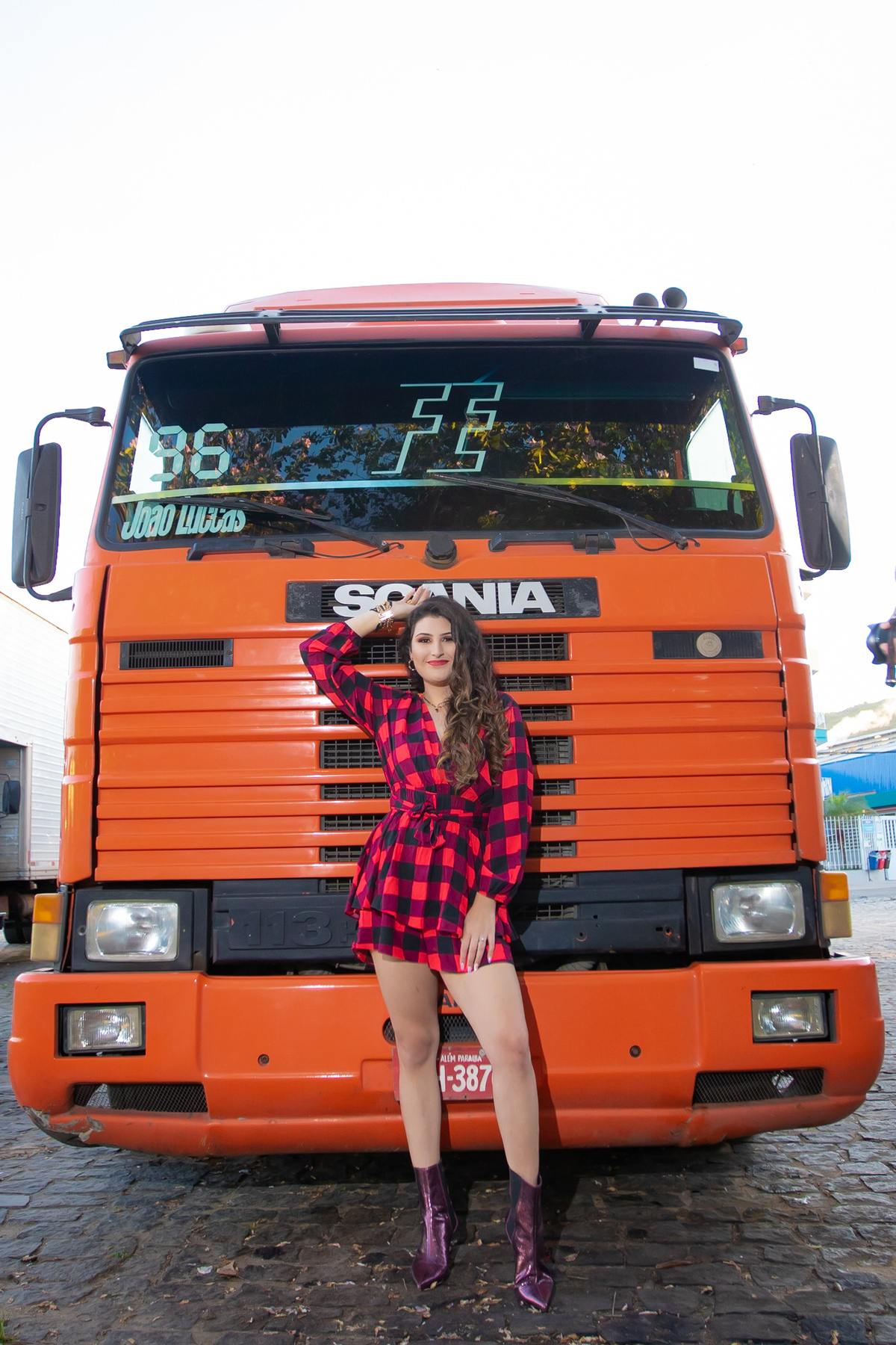 Ensaio de 15 , debutante sorrindo,  enfrete a uma carreta scaner, vestindo roupa xadrez em pôr do sol em um dia ensolarado em Santo Antônio de Pádua no interior do Rio de Janeiro.