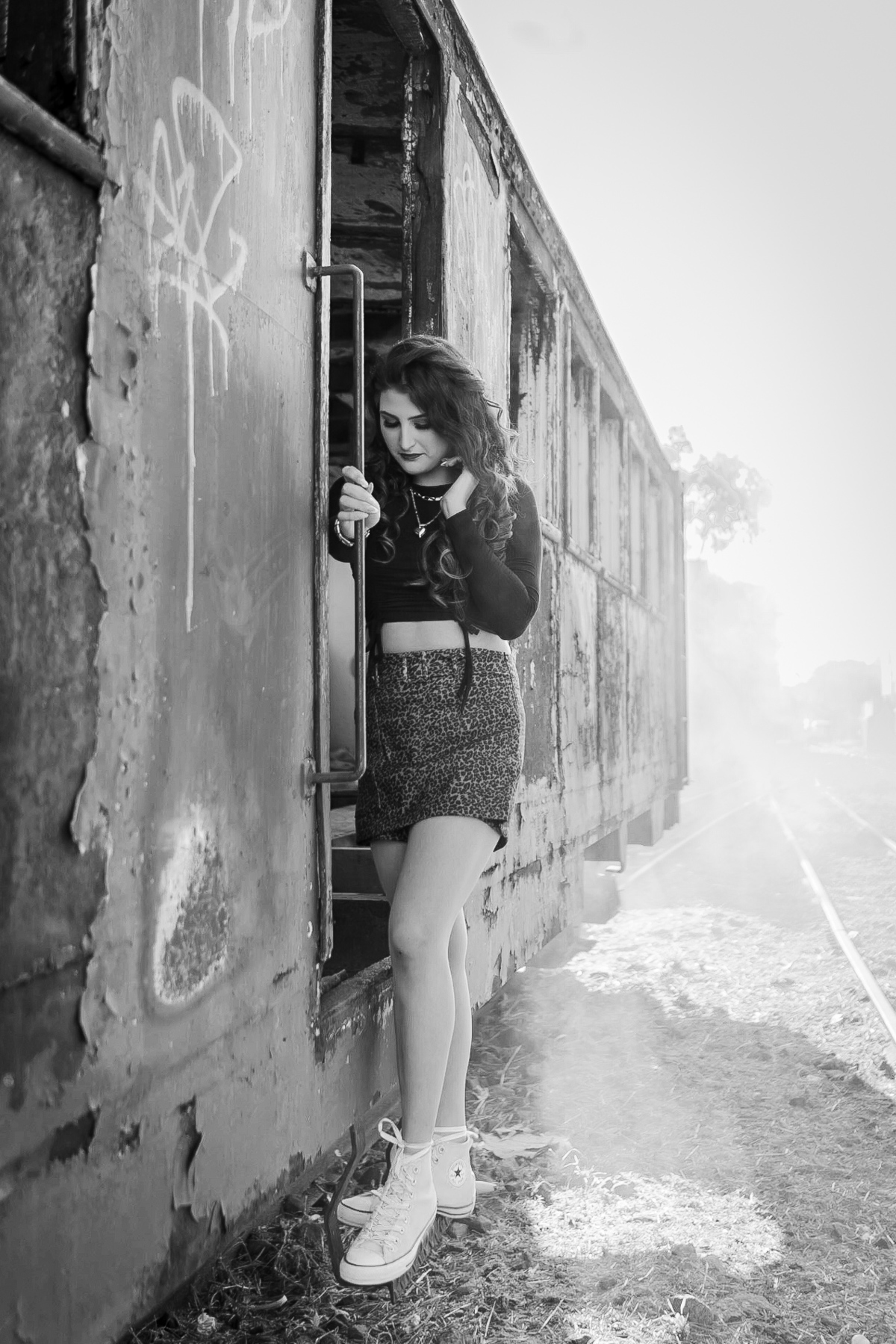 Ensaio de 15 anos em uma estação de trem antiga, a menina usando all satar laranja, com um toper preto e um short saia em animal print em um dia ensolarado em Santo Antônio de Pádua no interior do Rio de Janeiro. Foto em preto e branco. 