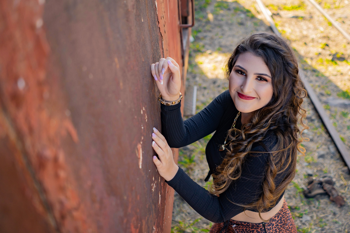 Ensaio de 15 anos em uma estação de trem antiga, a menina usando all satar laranja, com um toper preto e um short saia em animal print em um dia ensolarado em Santo Antônio de Pádua no interior do Rio de Janeiro.