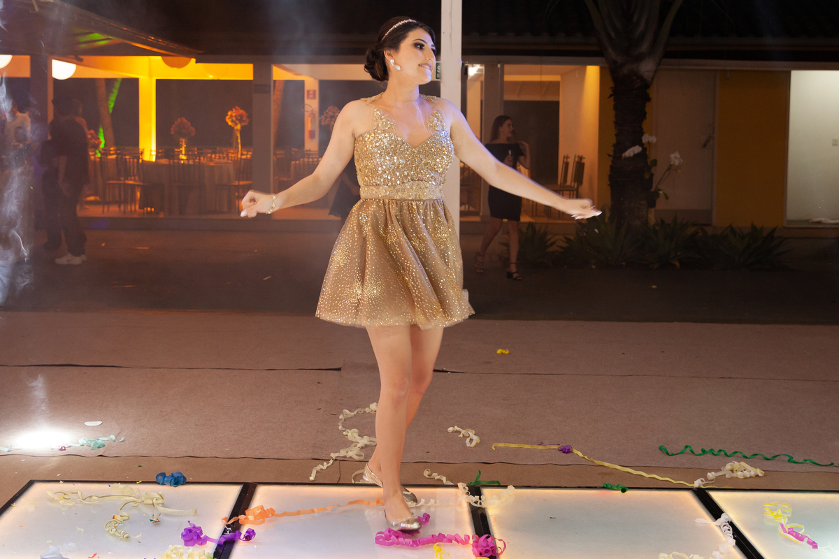 Debutante linda e feliz dançando em sua festa na pista de dança com Dj e Robô, com vestido dourado em maison saintec ecile em Santo Antônio de Pádua interior do Rio de Janeiro.