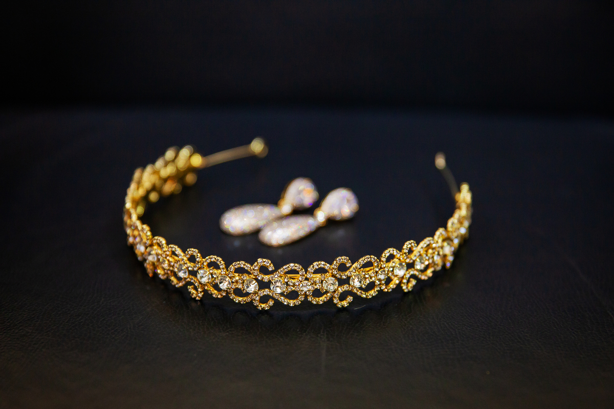 Making Of de debutante com detalhes dos brincos e tiara douradas e sapatos brancos lindos em salão de beleza studio make mean angel em Santo Antônio de Pádua interior do Rio de Janeiro.