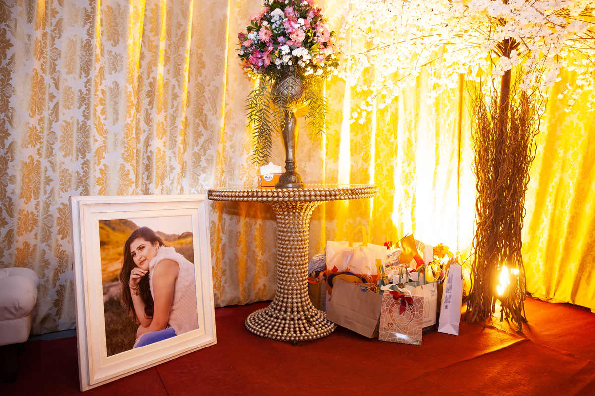 Decoração linda para festa de 15 anos em tons de vermelho e dourado com muitas flores naturais em maison saintec ecile e quadro fotográfico da debutante no tamanho 50x60 em Santo Antônio de Pádua interior do Rio de Janeiro.