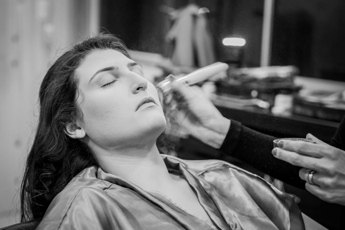 Foto em preto e branco. Making Of festa de 15 anos, debutante lindo com hobby dourado sendo maquiada em salão de beleza studio make mean angel em Santo Antônio de Pádua interior do Rio de Janeiro.