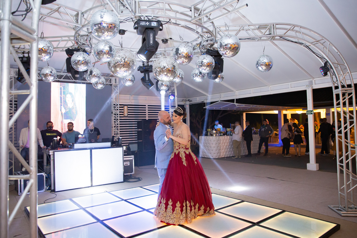 Pai e debutante com vestido lindo de vermelho e dourado dançando valsa durante a festa em salão de festa maison sainte cecile em Santo Antônio de Pádua interior do Rio de Janeiro.