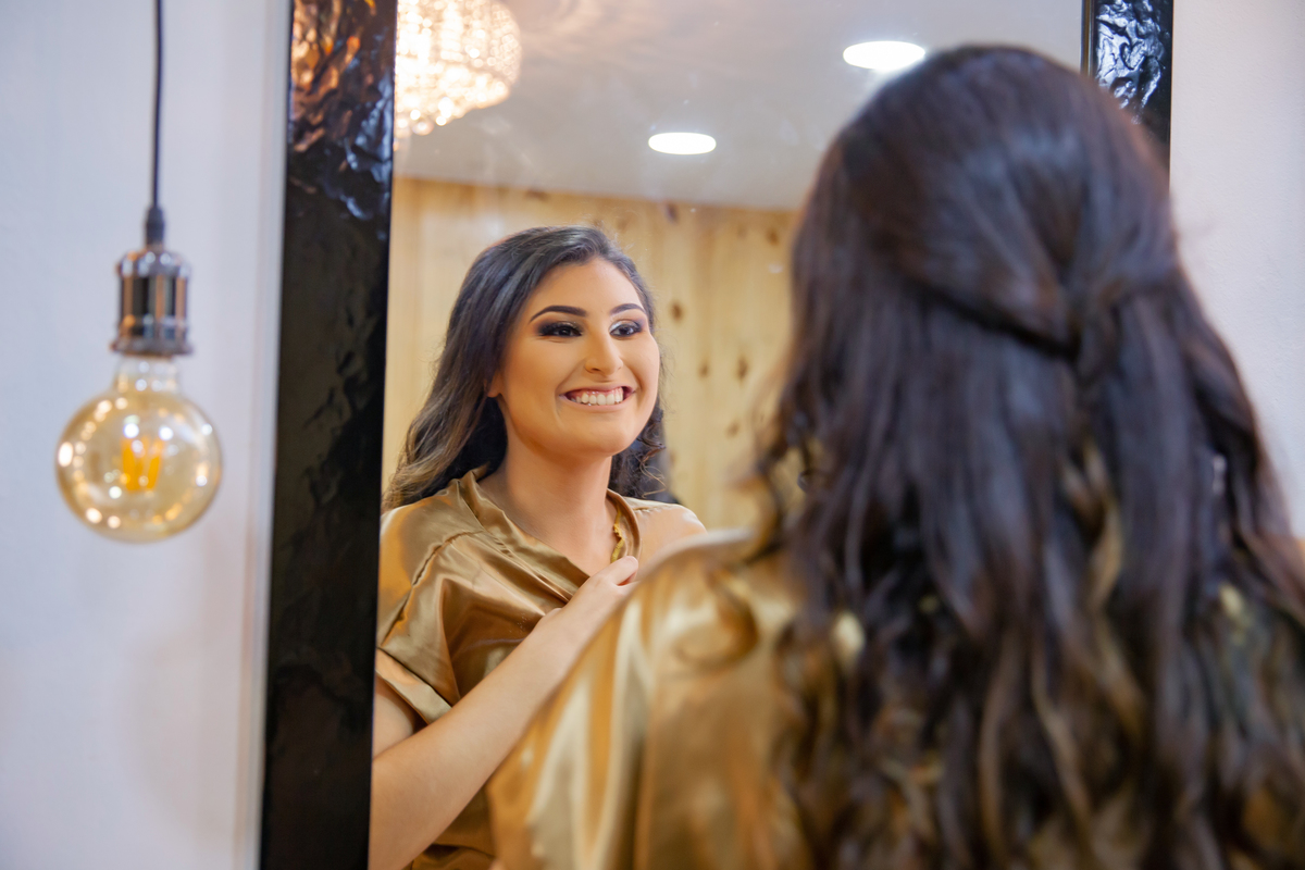 Making Of festa de 15 anos, debutante lindo com hobby dourado sendo maquiada em salão de beleza studio make mean angel em Santo Antônio de Pádua interior do Rio de Janeiro.