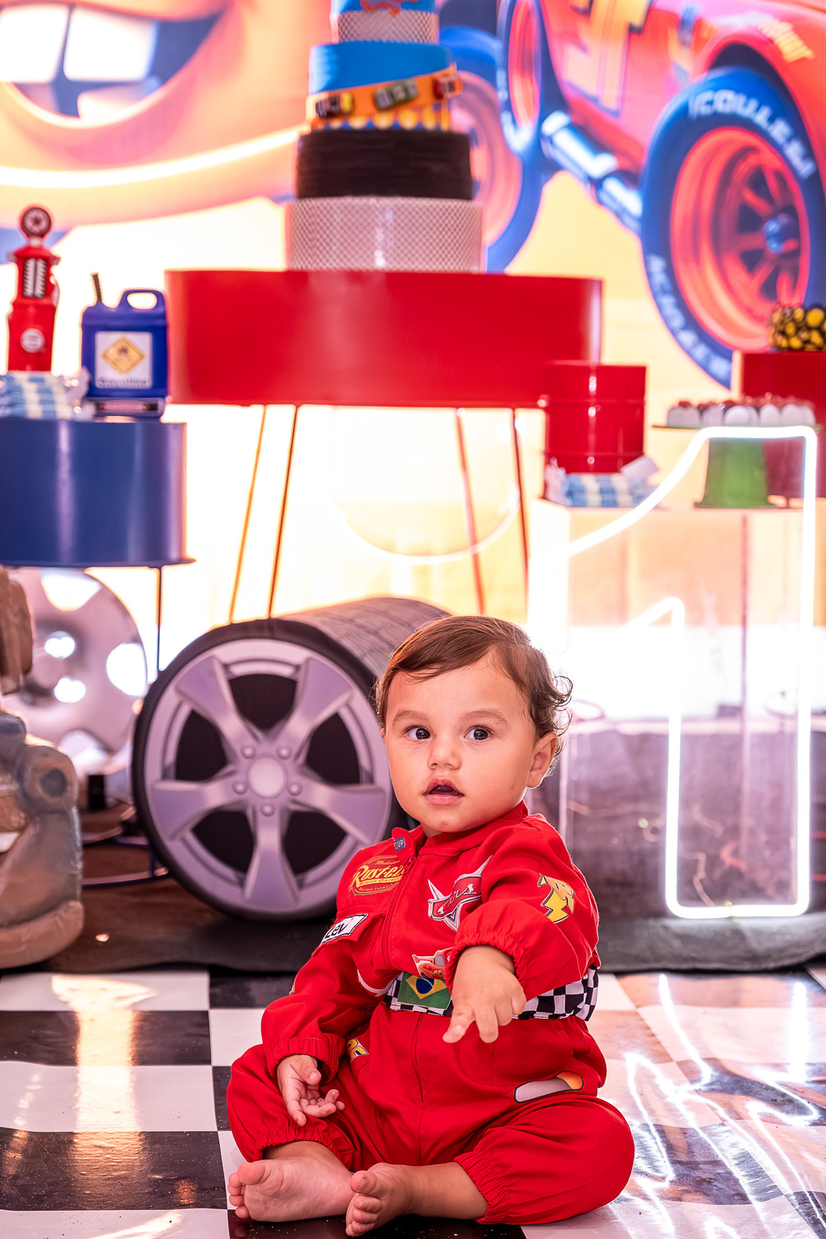 Levi observando a decoração da festa com o tema Carros, em um close-up encantador de fotografia infantil.