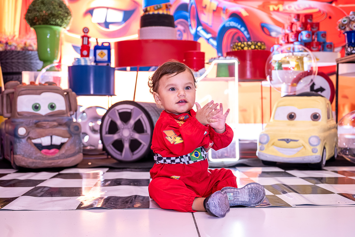 Levi explorando a mesa de doces com o tema Carros, em um momento de curiosidade na festa infantil.