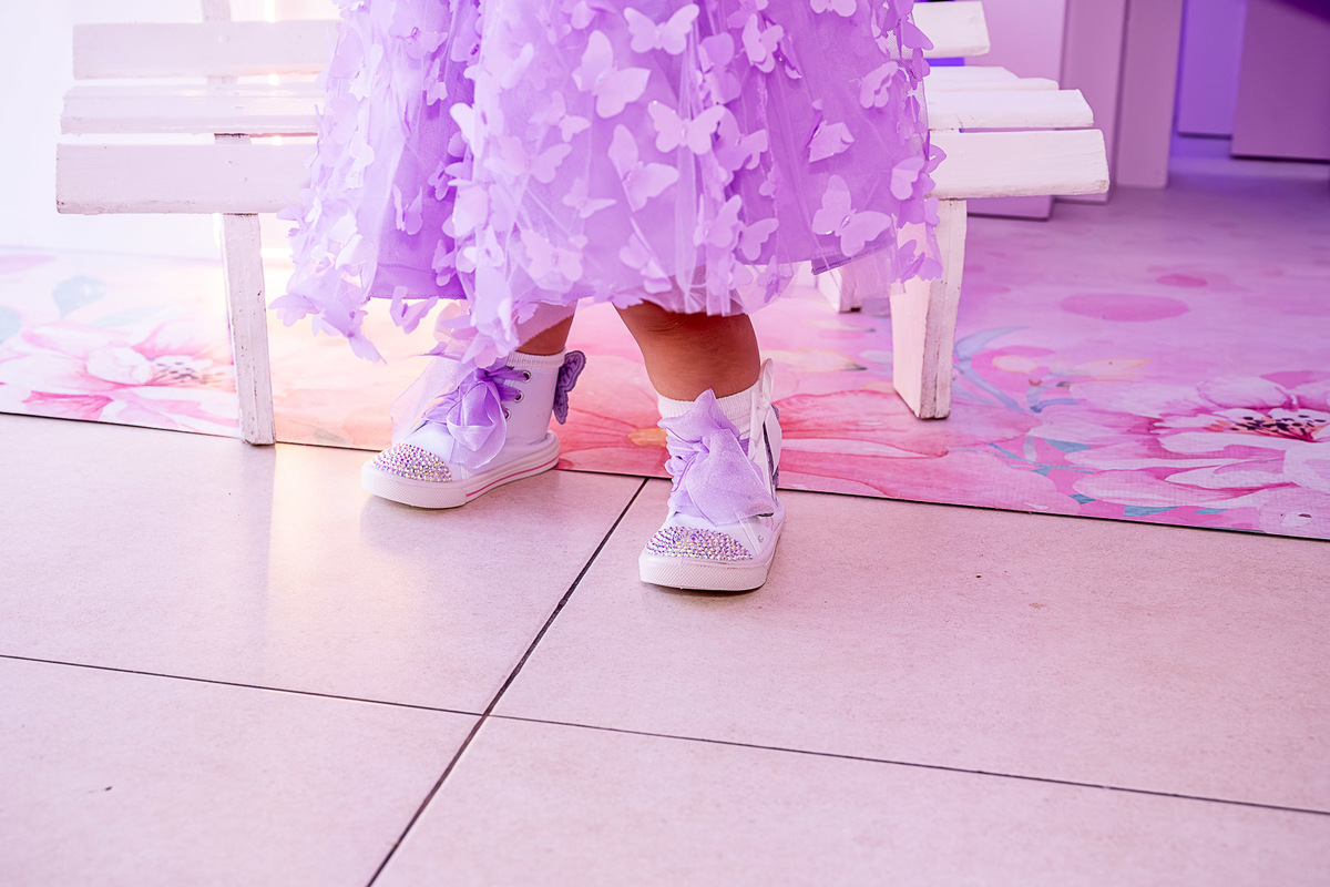 Cecília sentada em um banquinho decorativo do Jardim das Borboletas, em pose fofa.