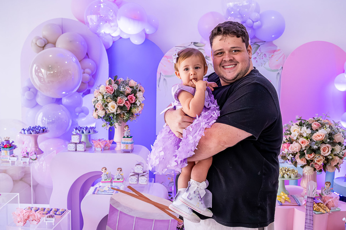 Cecília com o padrinho, em uma foto de família na festa infantil.