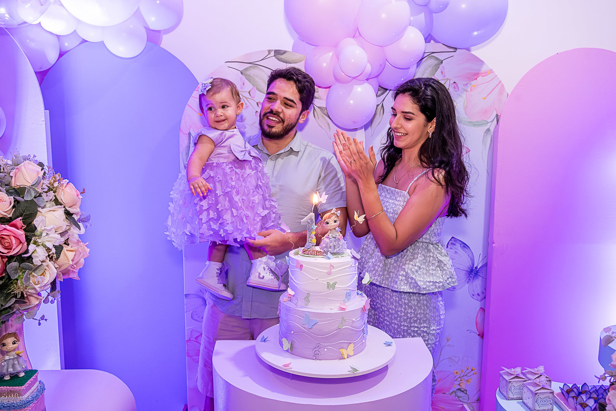 Momento do parabéns, com os pais cantando para a Cecília, em foto de aniversário infantil.