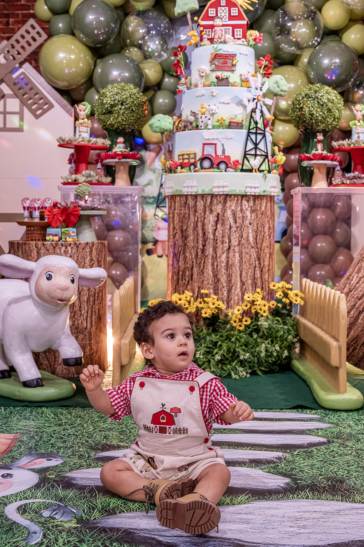 Renan em um banquinho rústico, com a decoração da Fazendinha ao fundo, no Castelo Encantado.