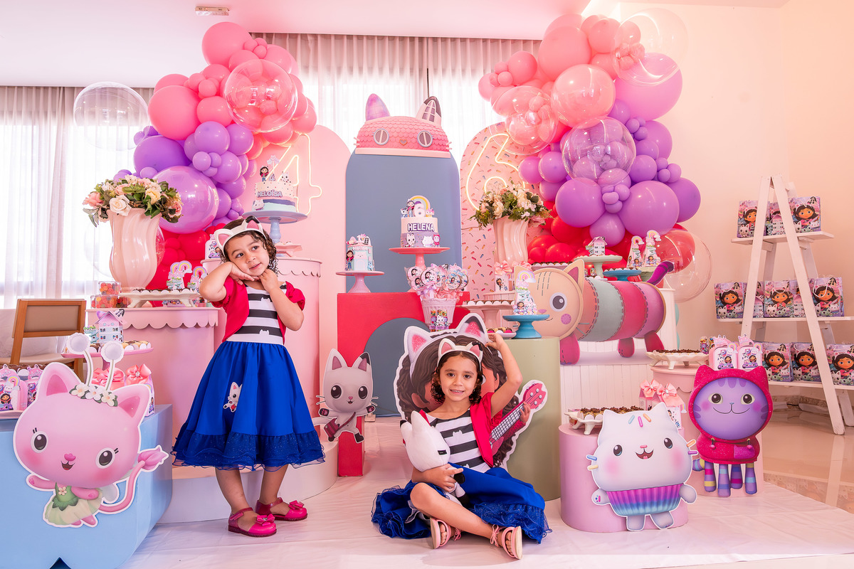 Helena e Heloísa posando juntas em frente à decoração da 