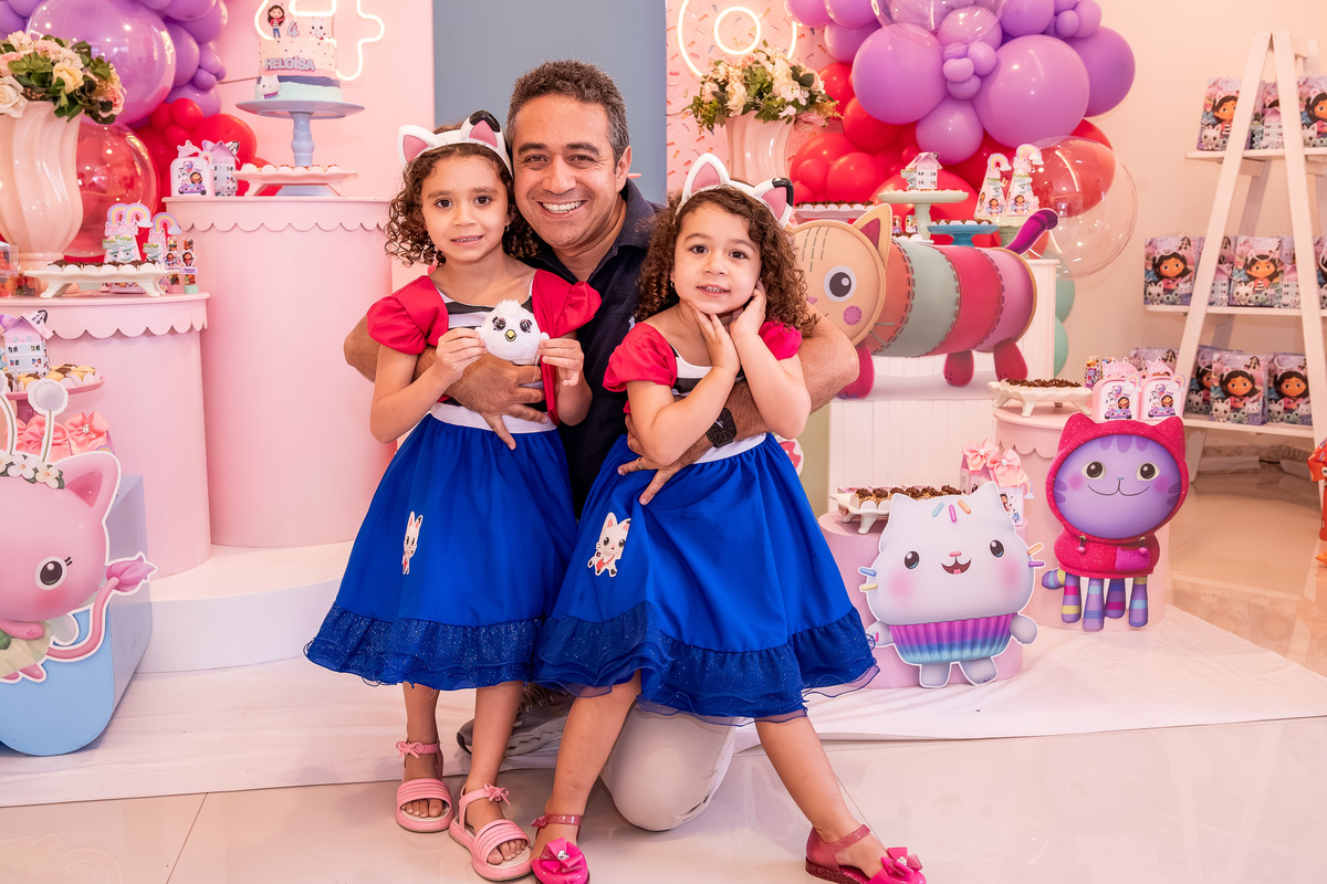Pai com Helena e Heloísa, em um momento de brincadeira e alegria na festa.