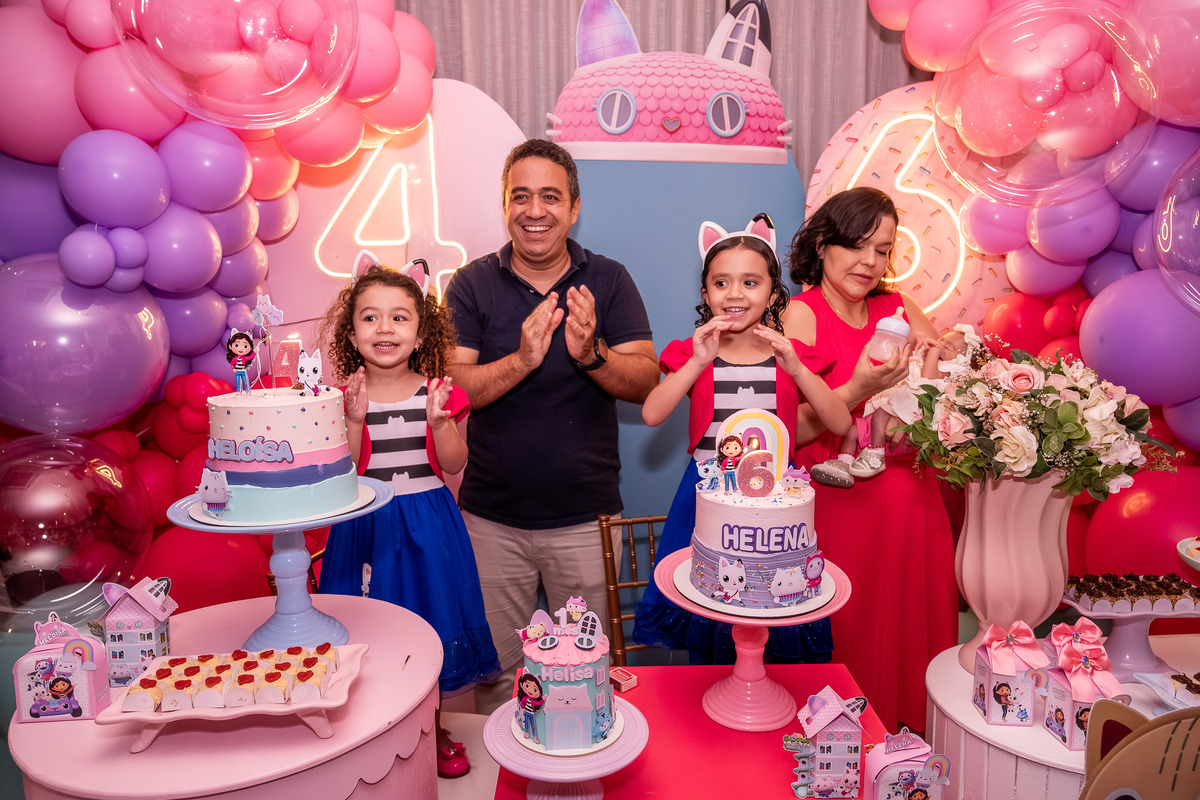 Helena e Heloísa sorrindo enquanto os convidados cantam parabéns, em Salvador.