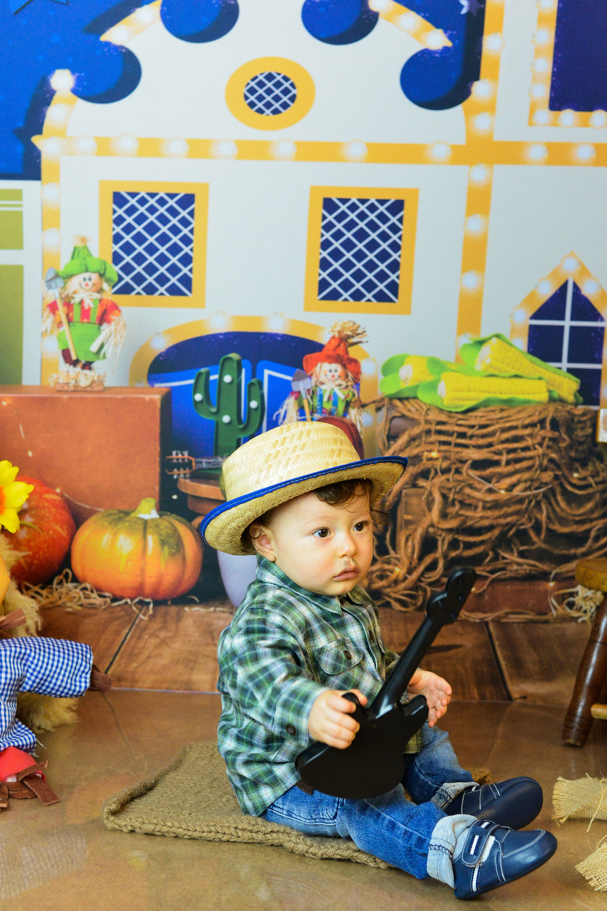 ensaio fotográfico realizado em estudio de menino, tema junino, camisa xadrez chapeu 