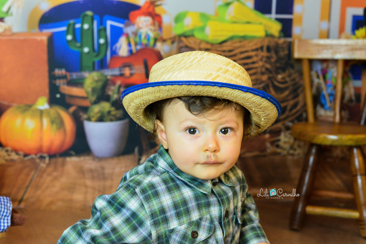 ensaio fotográfico realizado em estudio de menino, tema junino, camisa xadrez bigode 