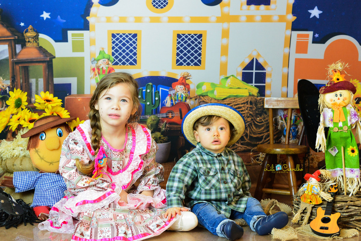 ensaio fotográfico realizado em estudio de menino, tema junino, camisa xadrez com irmã 