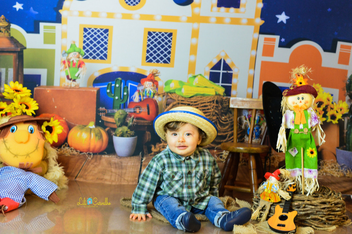ensaio fotográfico realizado em estudio de menino, tema junino, camisa xadrez sorrindo 