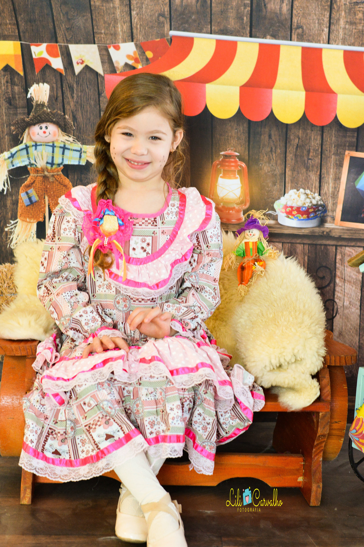 ensaio fotográfico realizado em estudio de menino, tema junino, camisa xadrez vestido rosa 