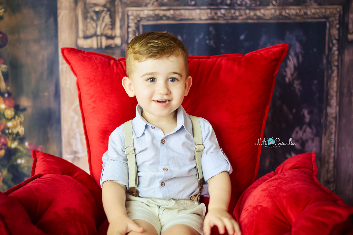 ensaio fotografico no estúdio em Maringá sentando em uma poltrona vermelha