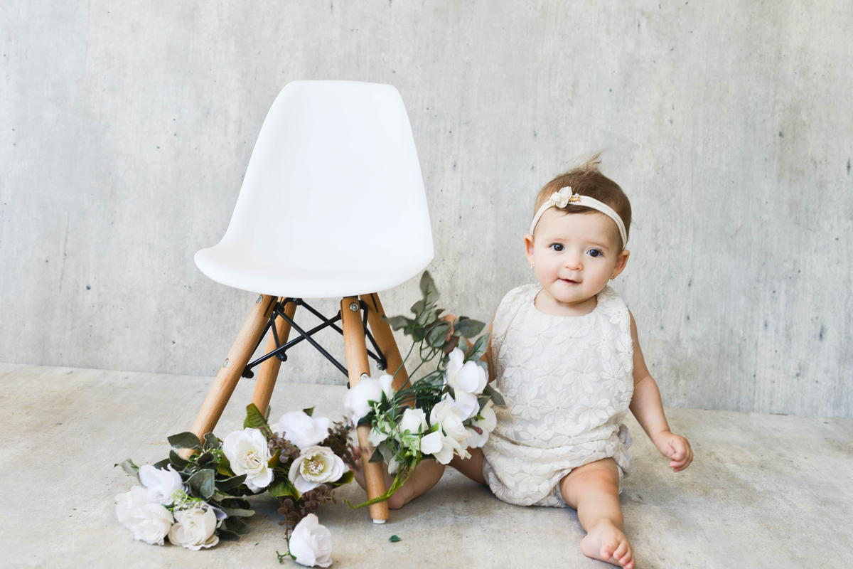 foto de bebê menina, fundo claro, estudio em Maringá olhando para lado 