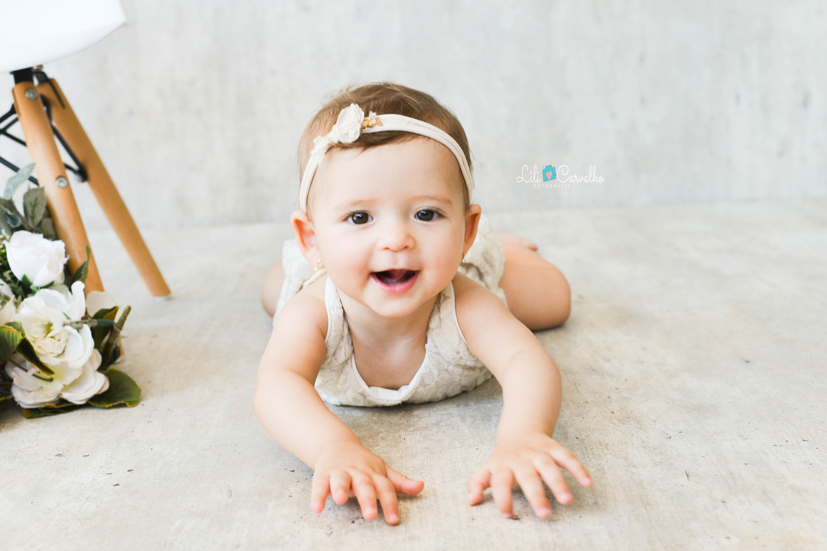 foto de bebê menina, fundo claro, estudio em Maringá engantinhando sorrindo