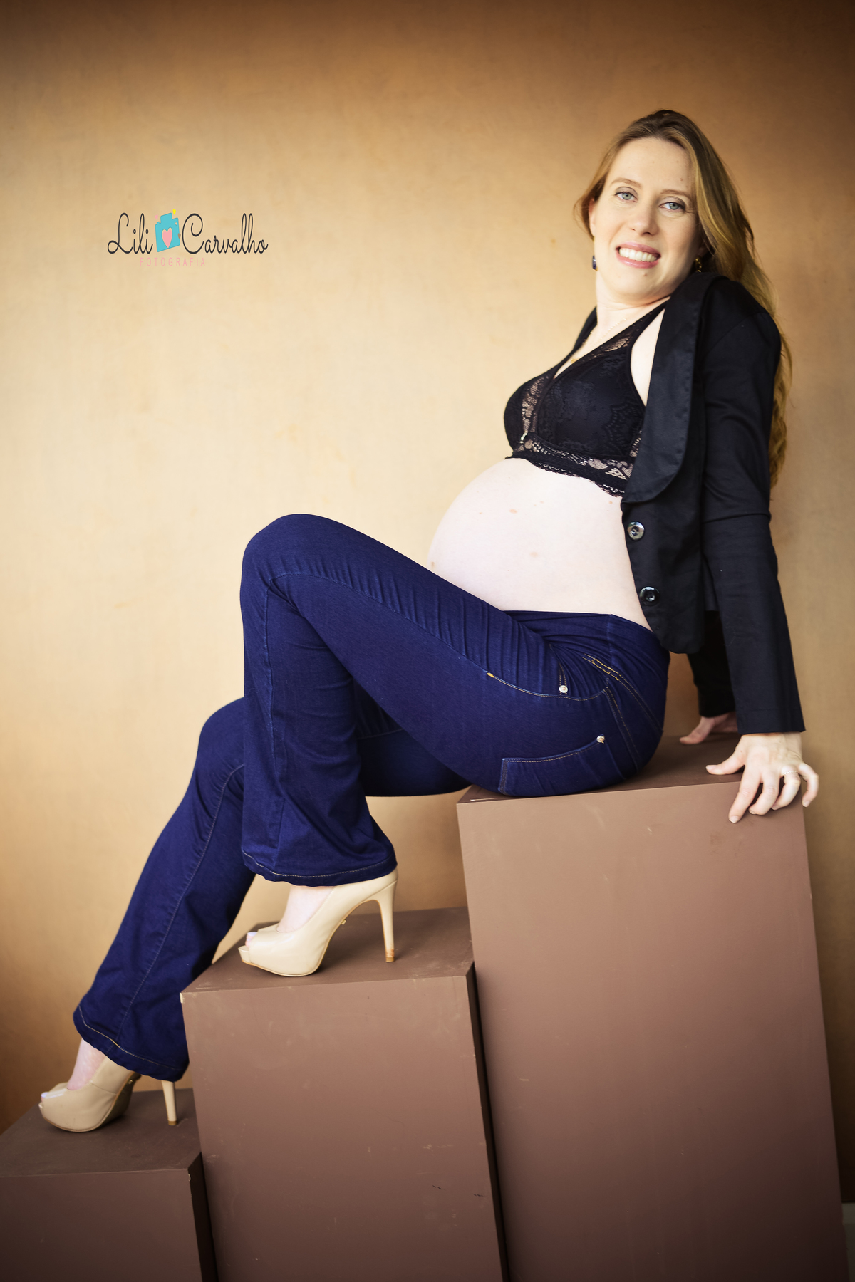 fotografia de gravida em estudio em maringa sentada sorrindo 