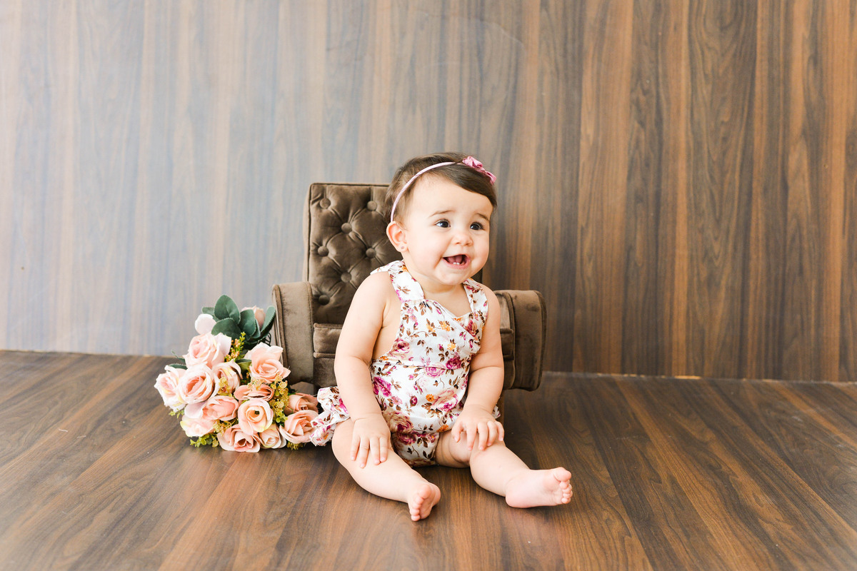fotografia mensal de  menina em Maringá, menina sentada em sofa, sorrindo