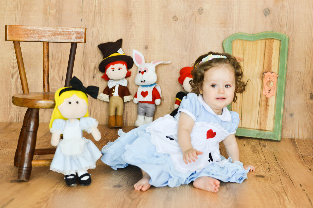 criança sentada, vestida de Alice no país das maravilhas