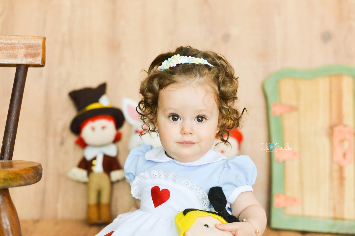 criança sentada, atenta a fotografia  vestida de Alice no país das maravilhas